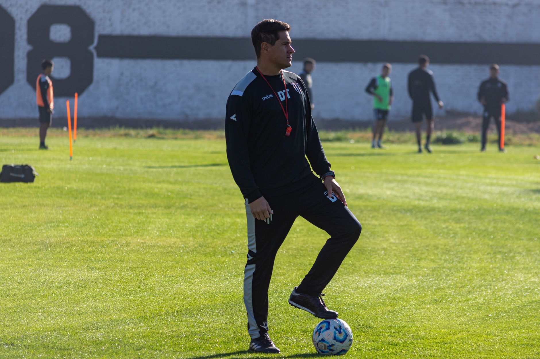 A coach on the training pitch with a ball under his arm